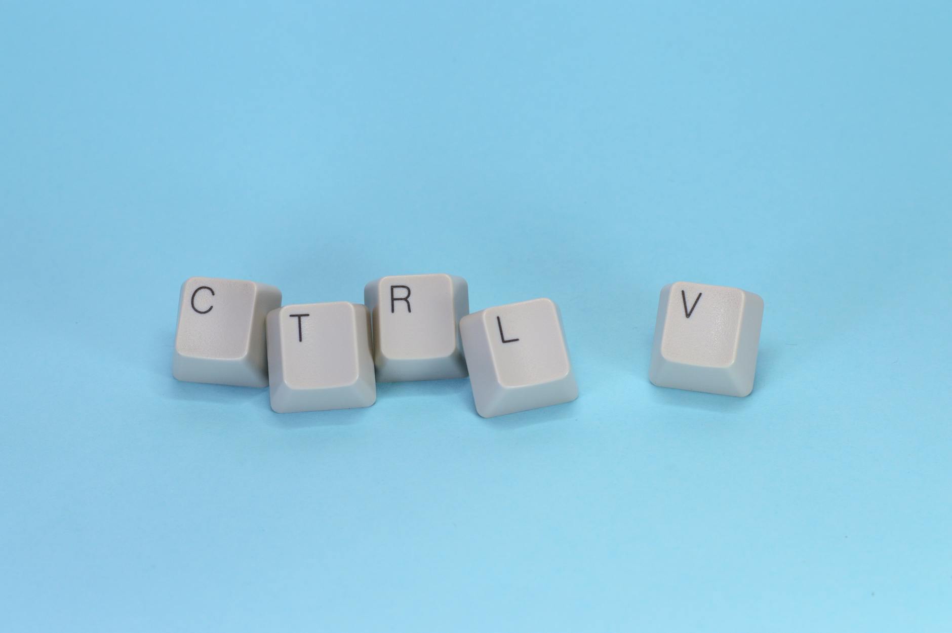 Close-up of CTRL V keyboard keys on a blue background. Minimalist tech concept.
