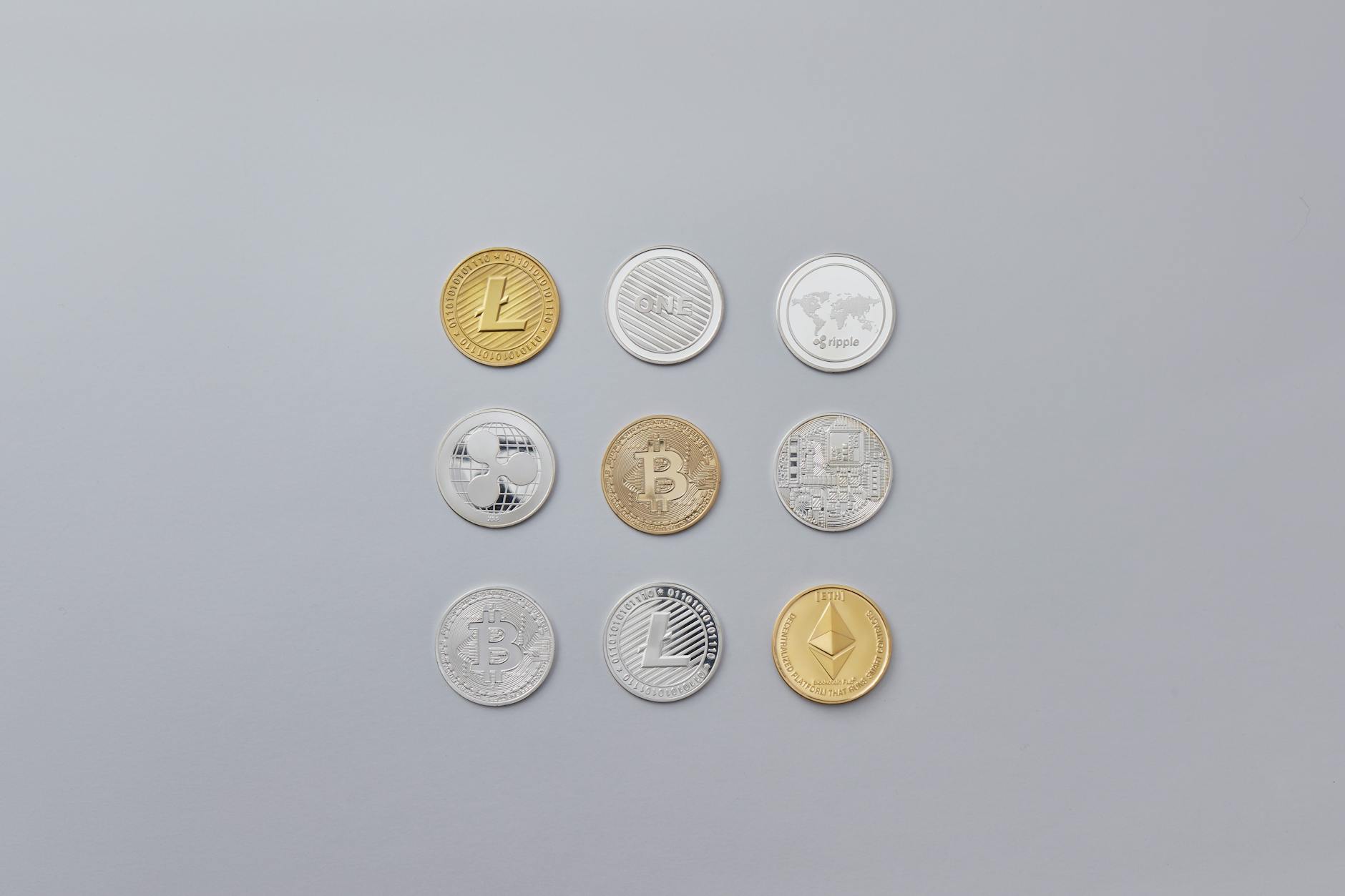 Image showcasing a selection of different cryptocurrency coins arranged on a neutral grey background.