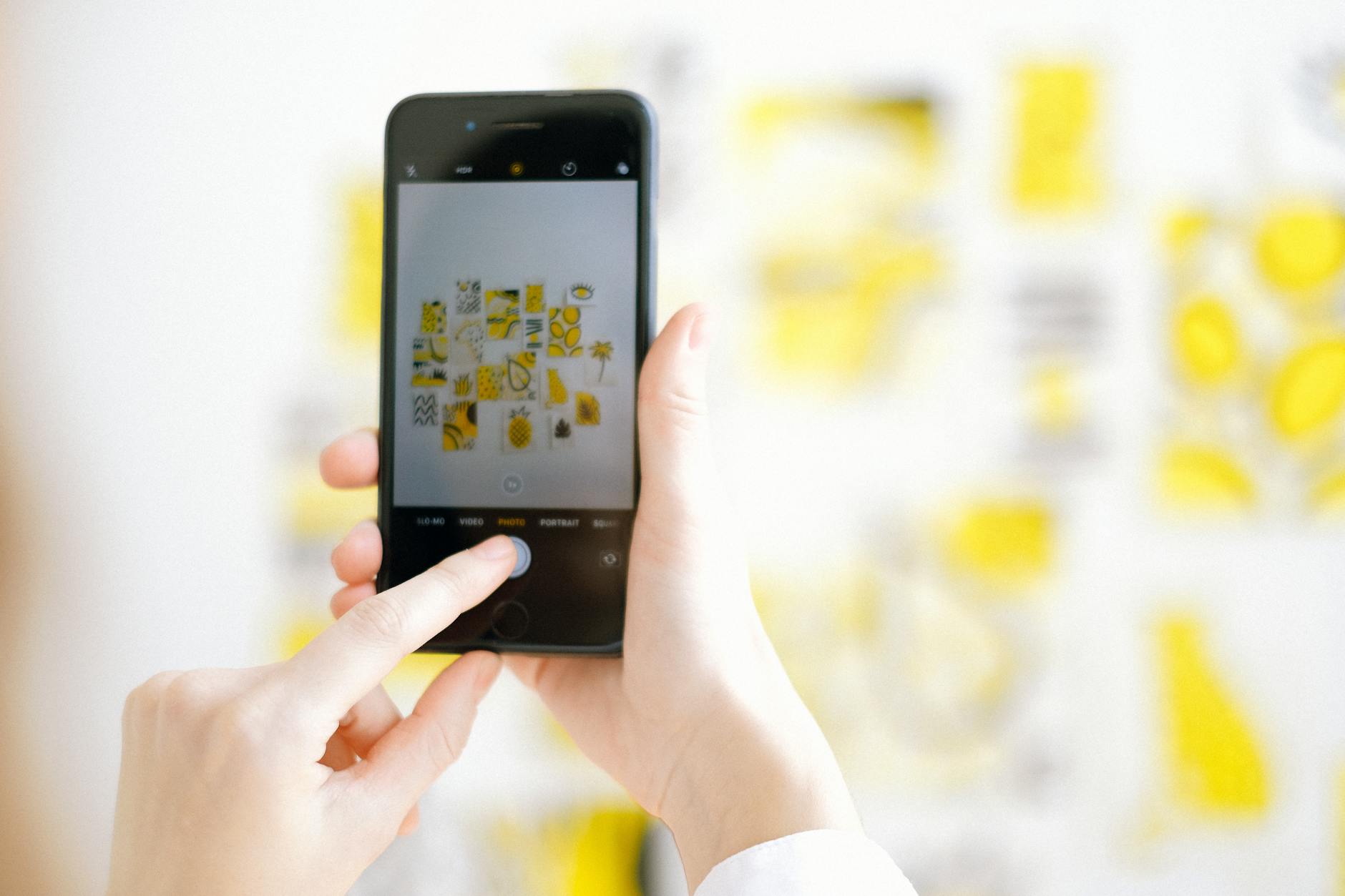 Close-up of a person taking photos of art pieces with a smartphone, focusing on modern technology.