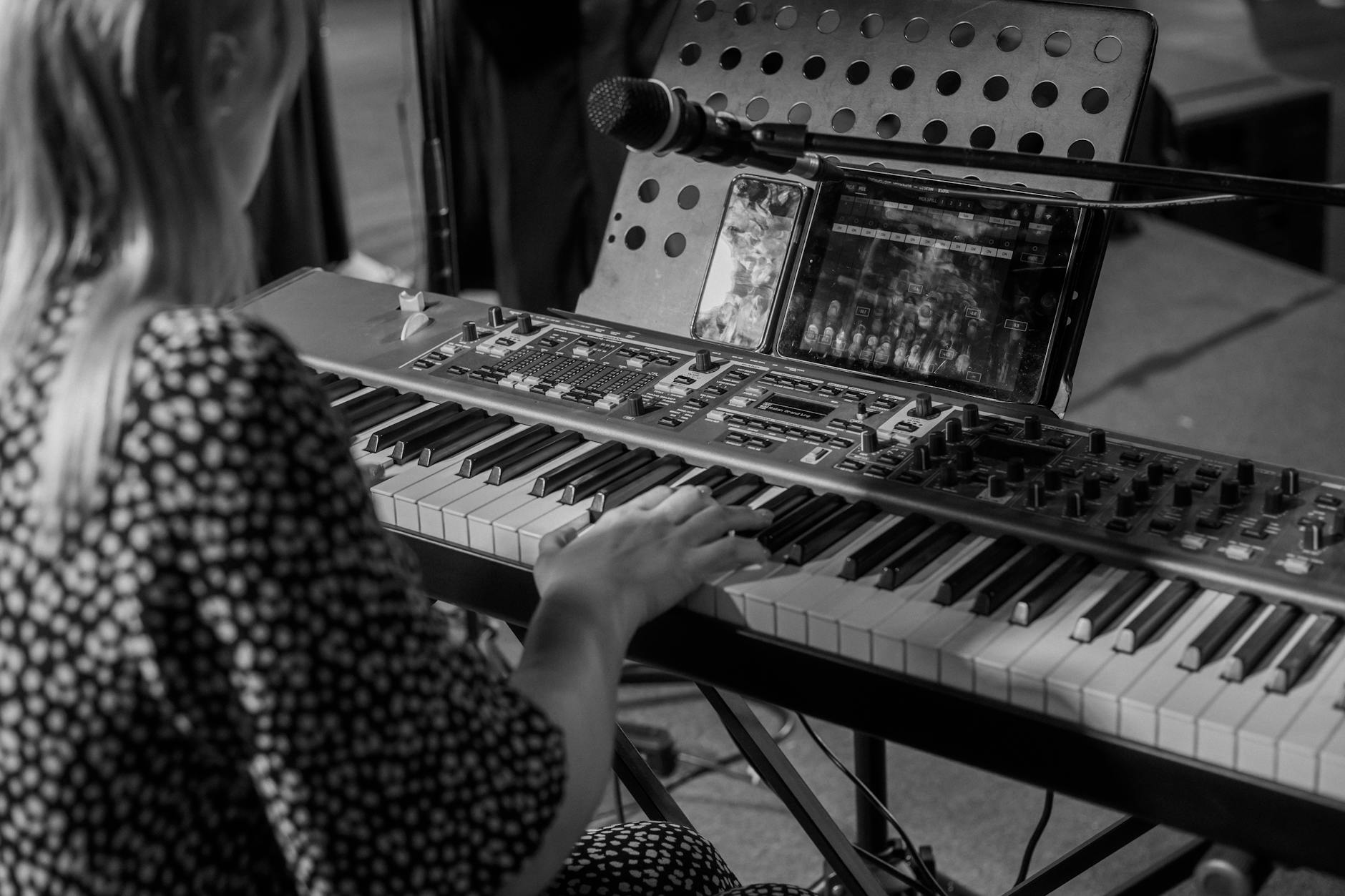 A woman playing a keyboard in a monochrome music setting. Artistic and professional.