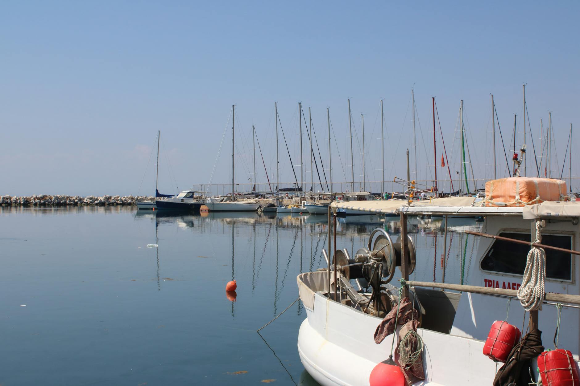 Tranquil view of moored boats in Thessaloniki harbor, Greece, reflecting on calm sea.