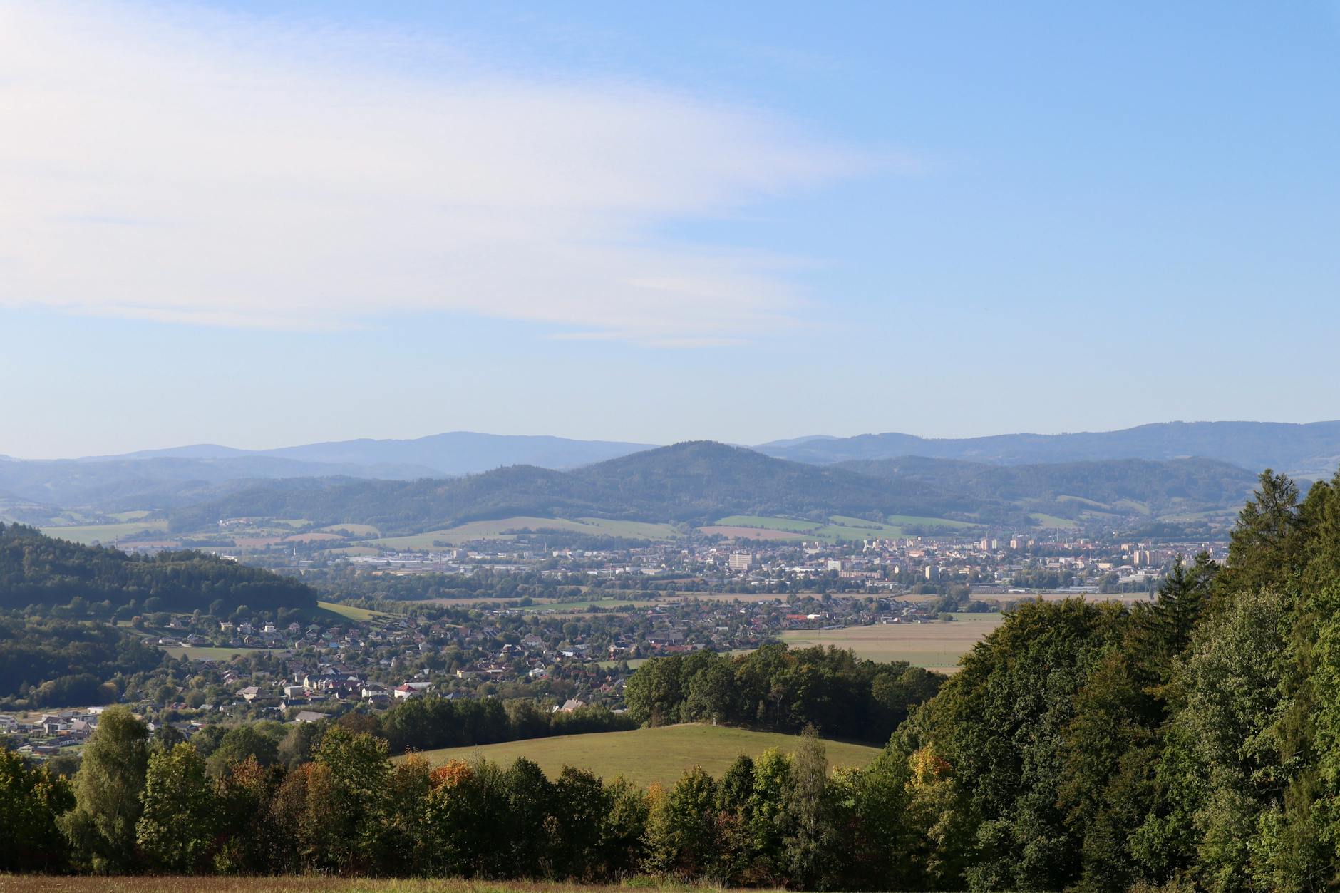 Panoramic view of a city surrounded by hills with a clear blue sky in the background.