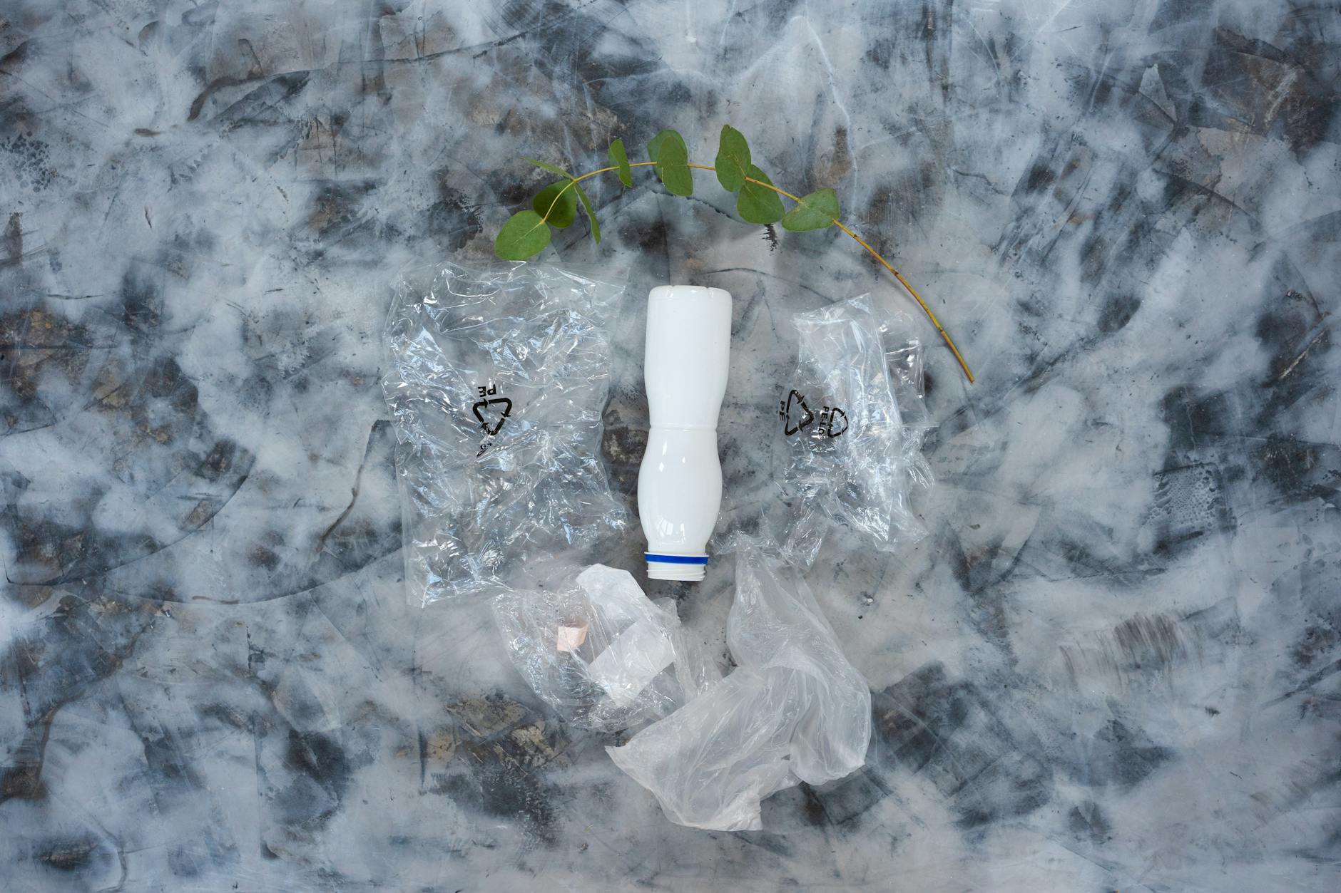 Conceptual still life of plastic waste and a leaf, symbolizing pollution.