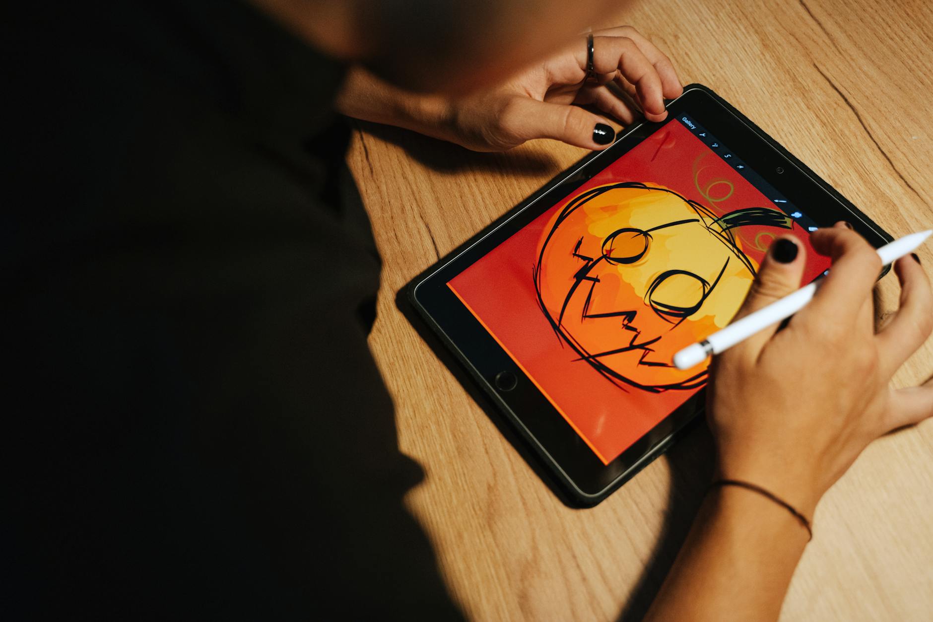 Creating a Halloween pumpkin illustration on a tablet with a stylus.