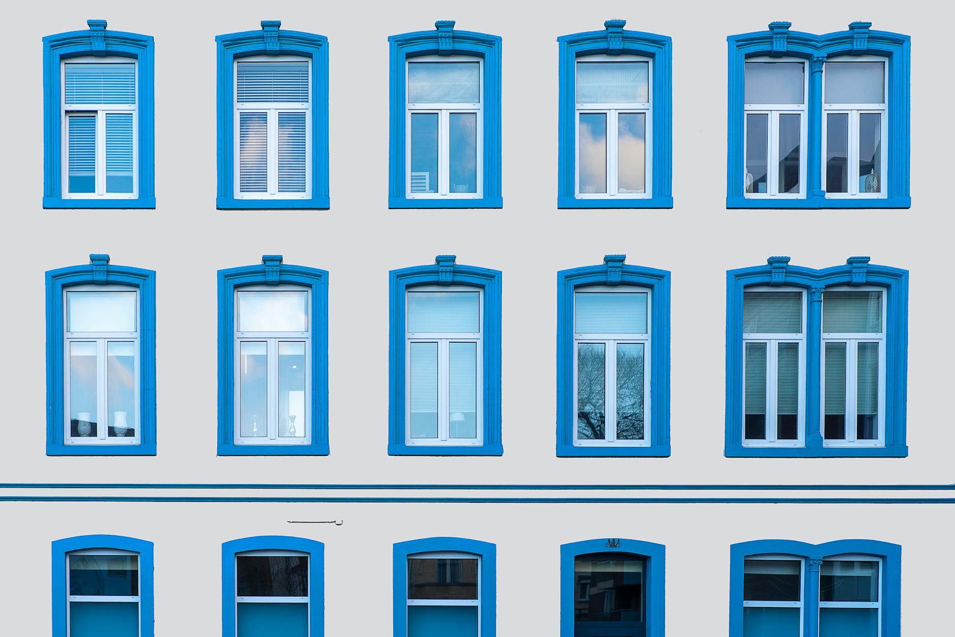 A symmetrical building facade with striking blue window frames in Valkenburg, Netherlands.