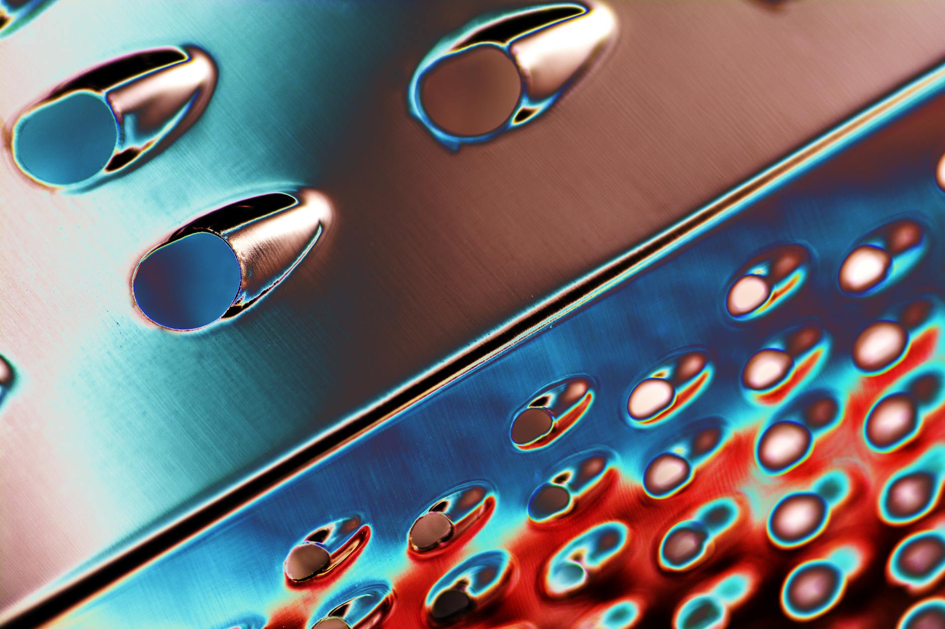 Macro shot of a shining stainless steel cheese grater. Vivid lighting accentuates its metallic texture.