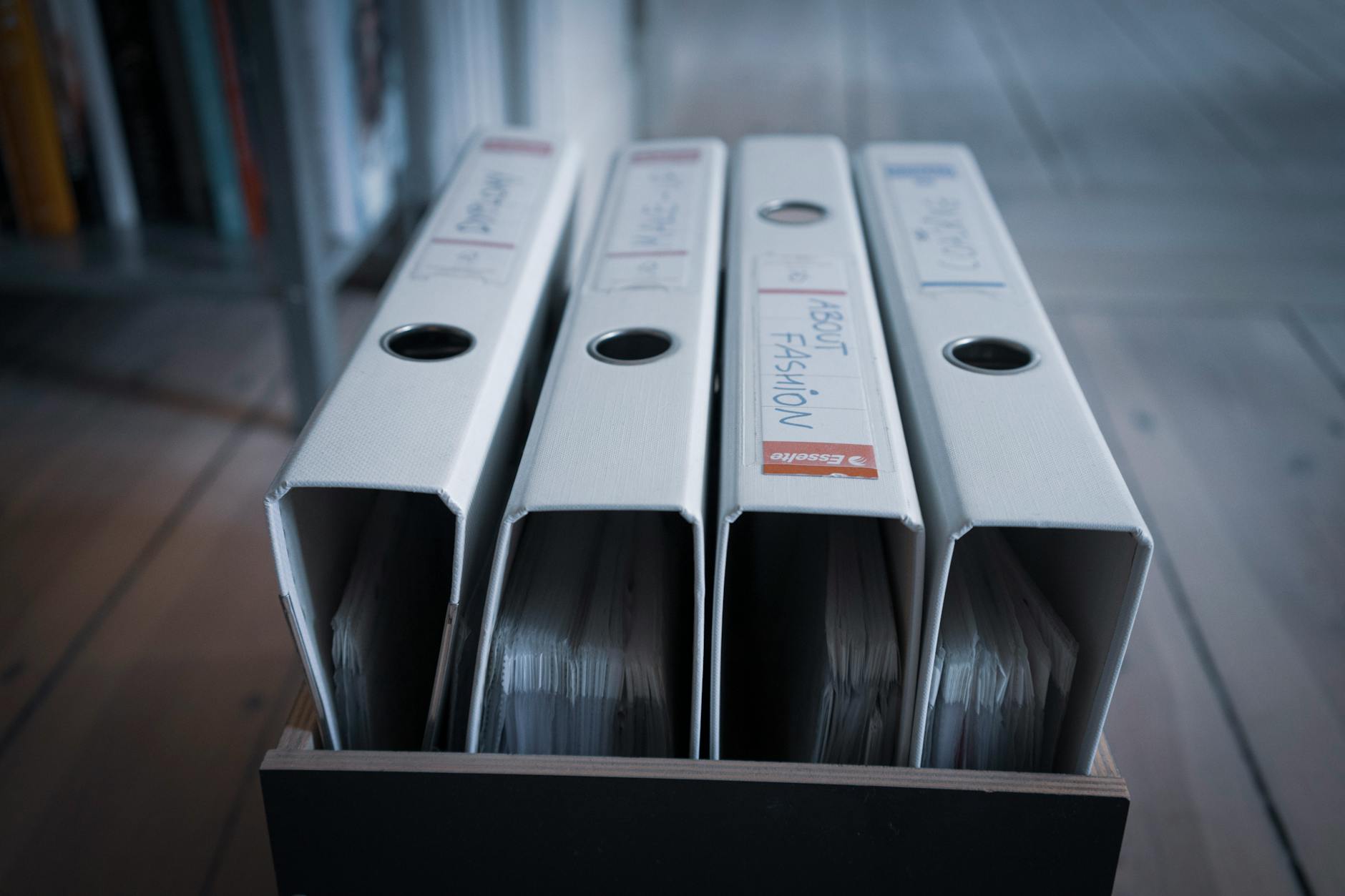 From above of similar folders with plastic sleeves and titles on surface in wooden box on floor