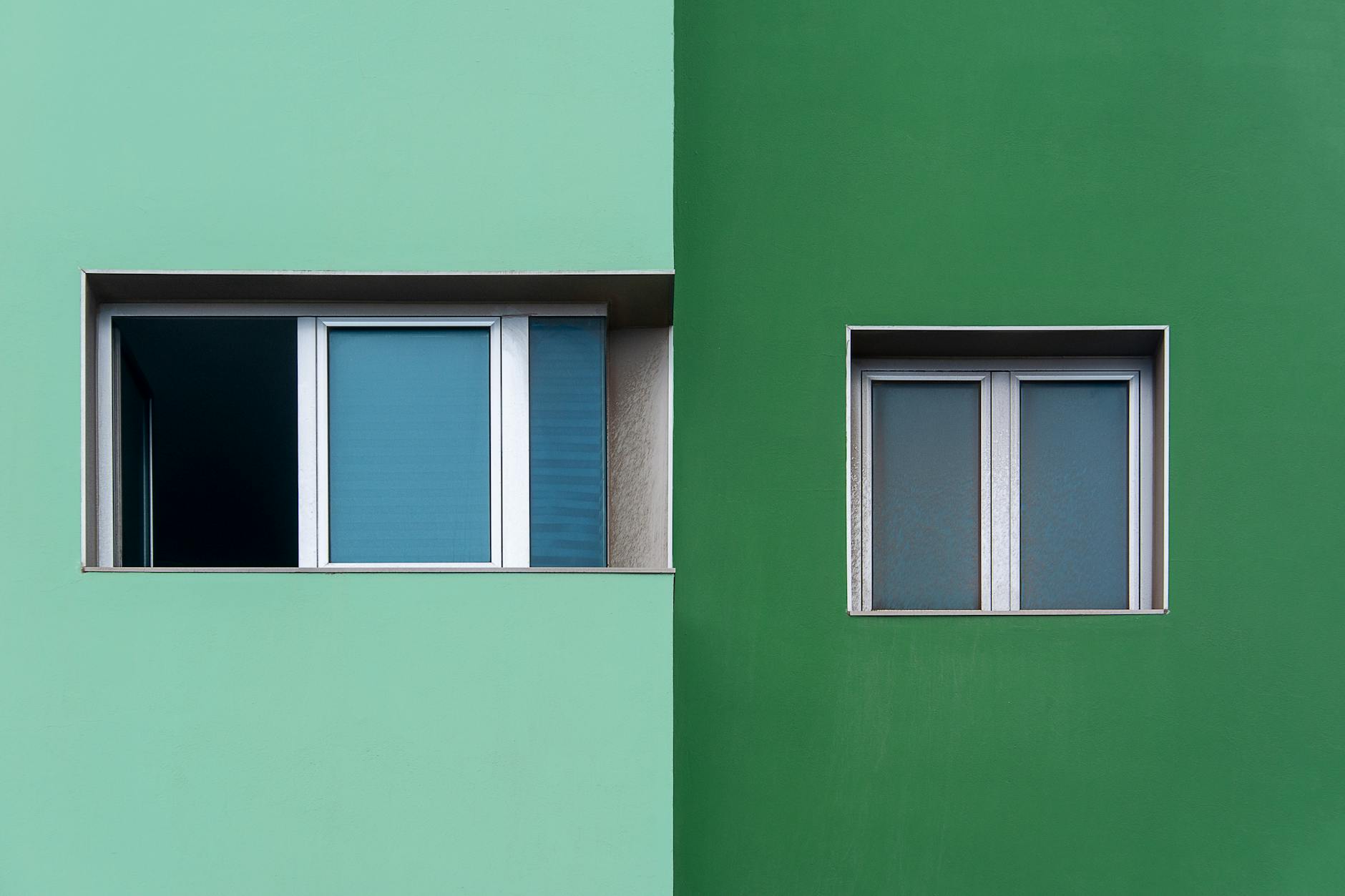 Minimalist facade showcasing two windows on contrasting green walls.