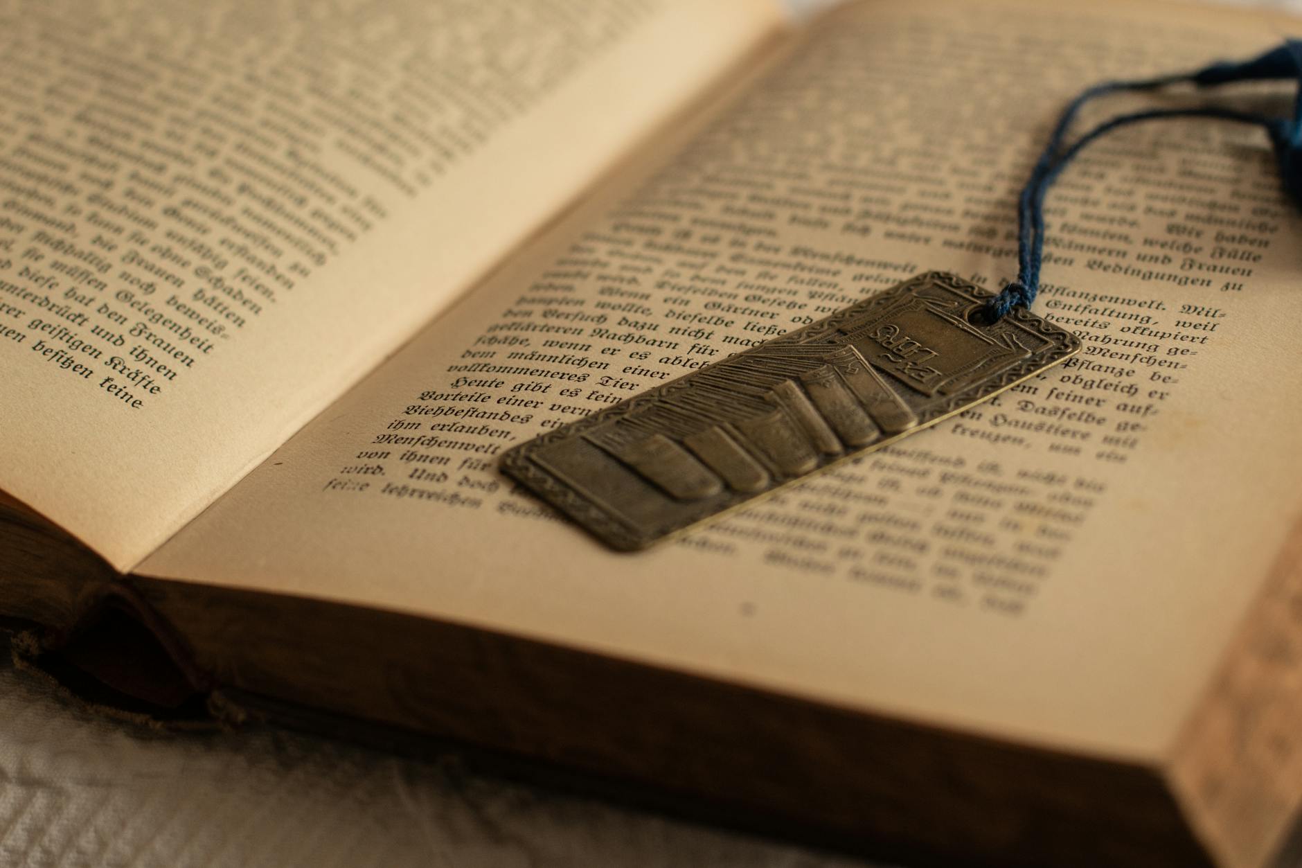 Explore a vintage book with a detailed metal bookmark resting on an open page, invoking a literary and nostalgic ambiance.
