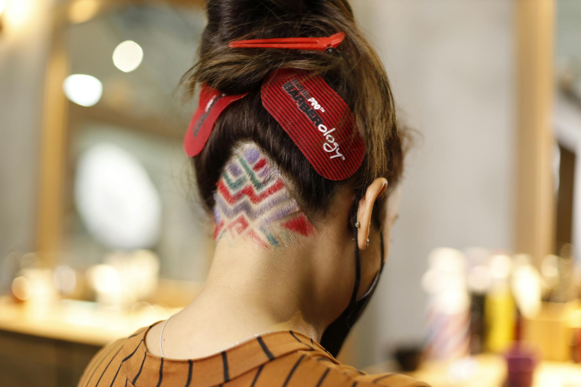 Close-up of a woman's geometric dyed hairstyle with vibrant colors in a salon.