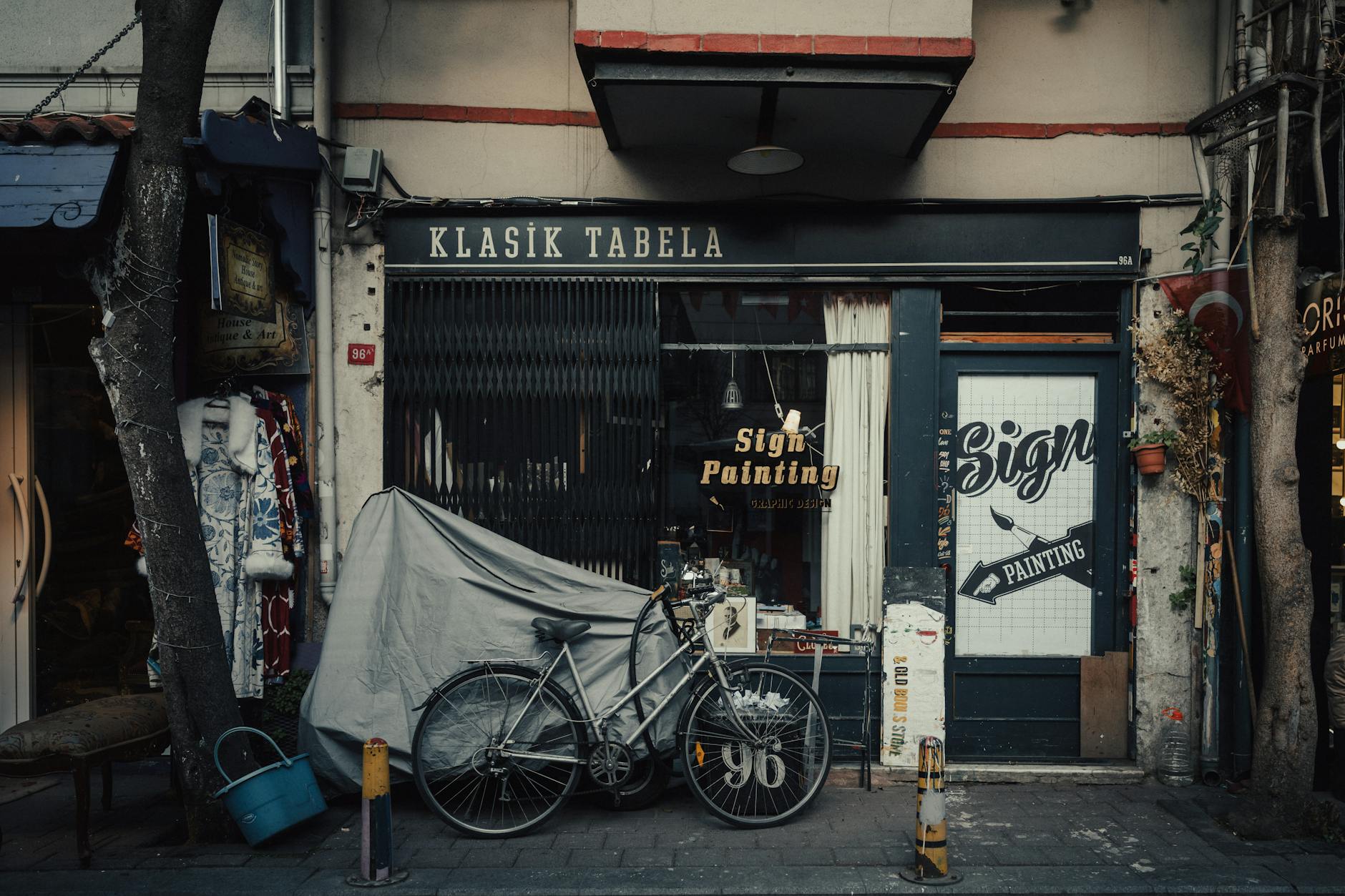 A vintage bicycle parked in front of a classic signage shop on an Istanbul street.