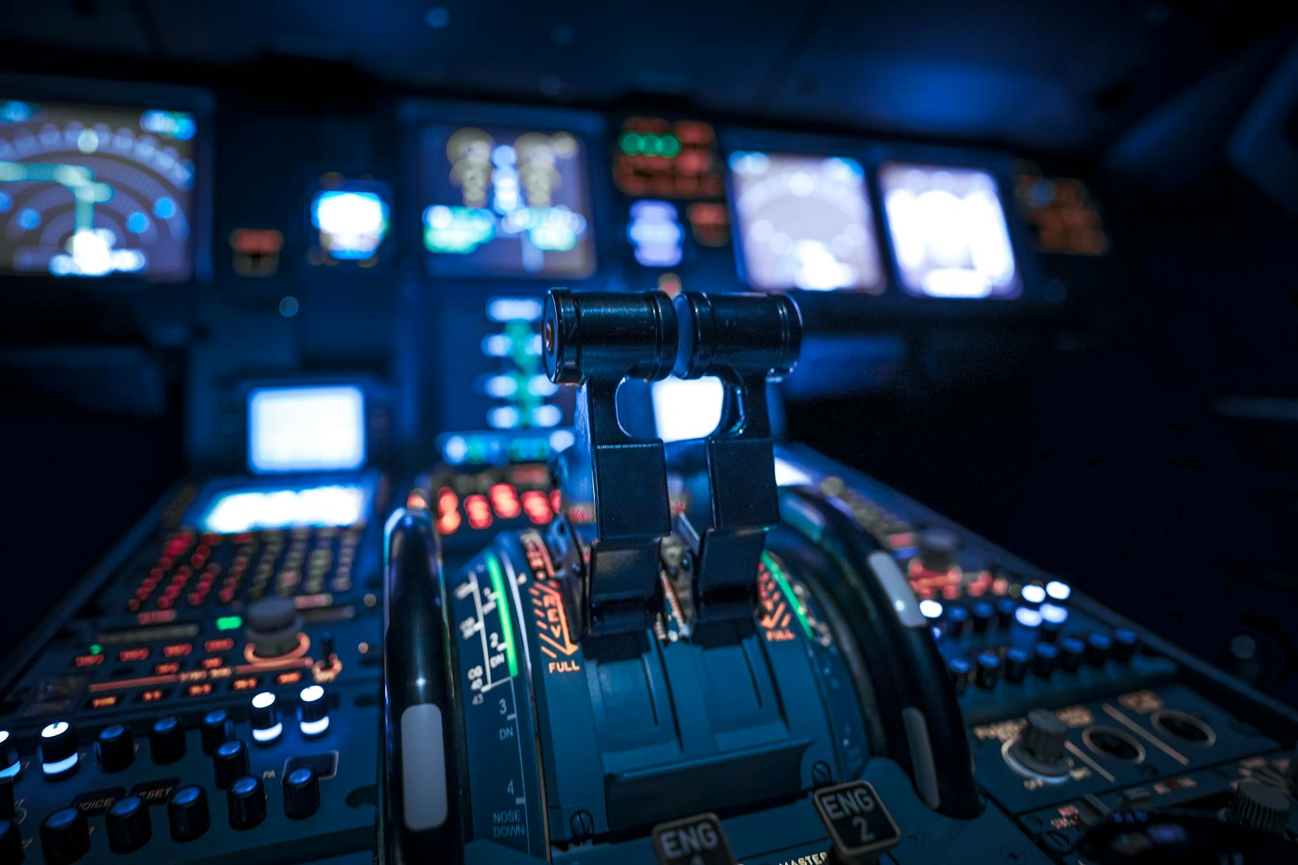 Close-up of a commercial aircraft cockpit with illuminated control panels and levers, showcasing aviation technology.