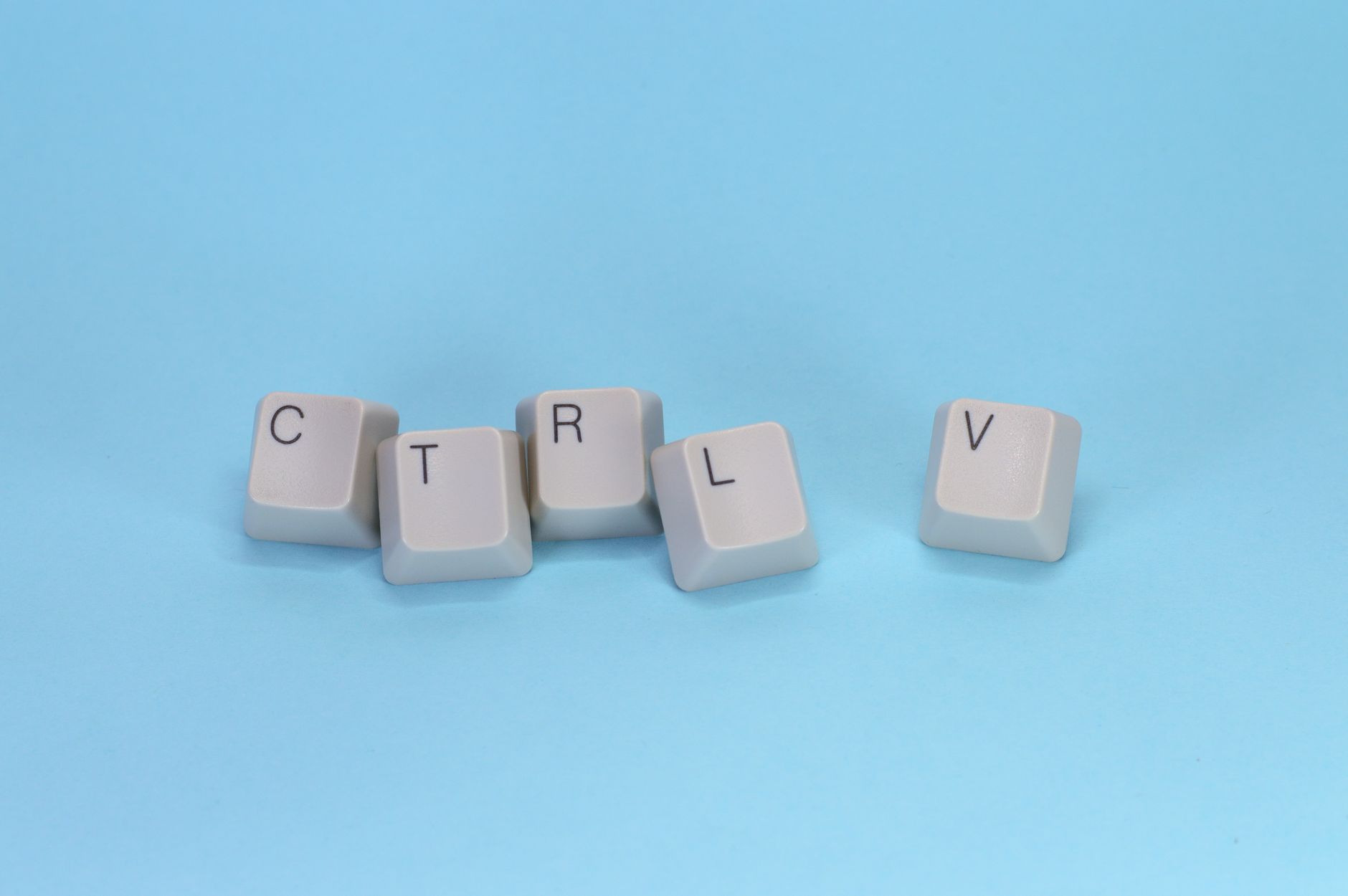 Close-up of CTRL V keyboard keys on a blue background. Minimalist tech concept.