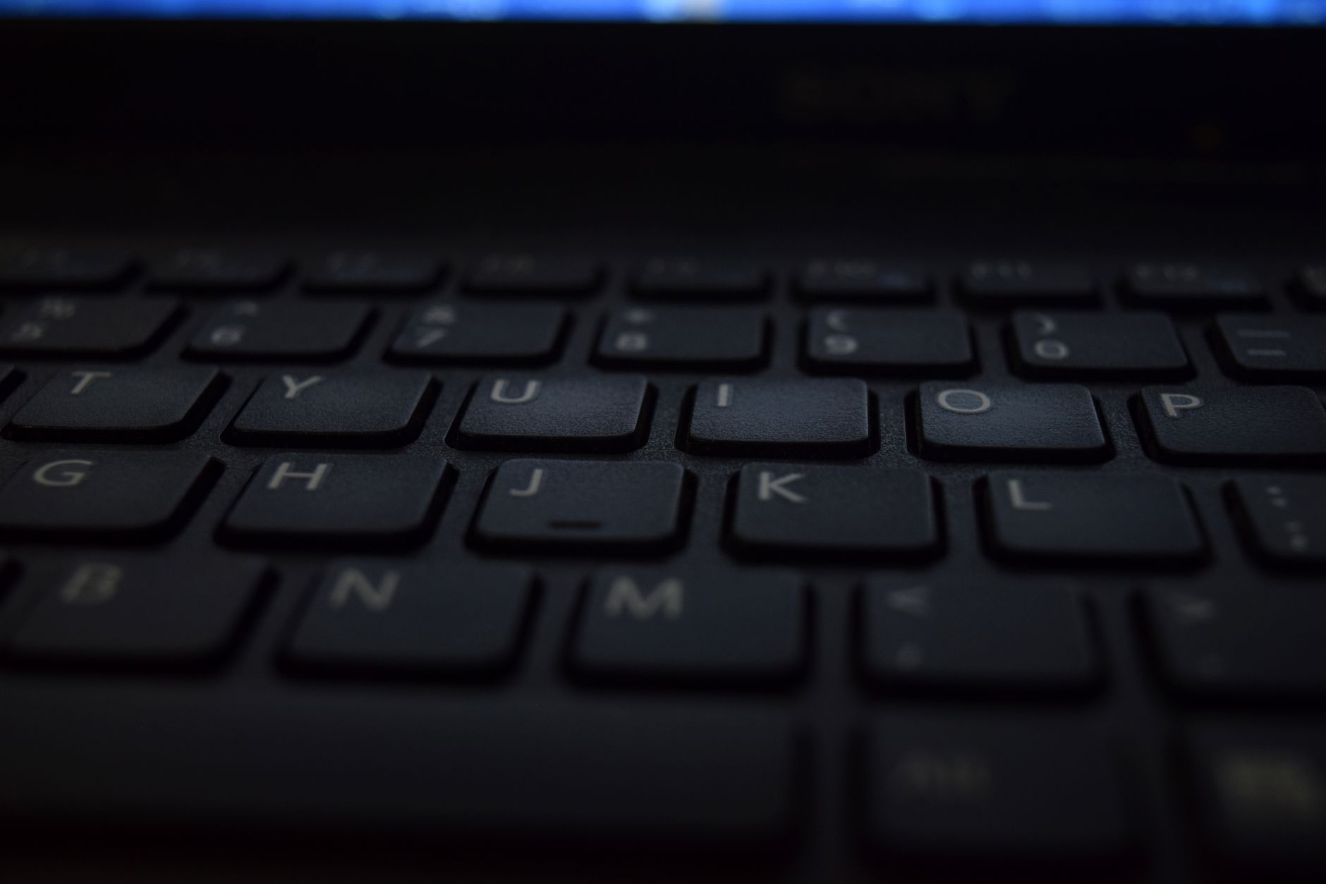 Zbliżenie klawiatury laptopa – podkreślnik dzieli klawisz z minusem obok zera