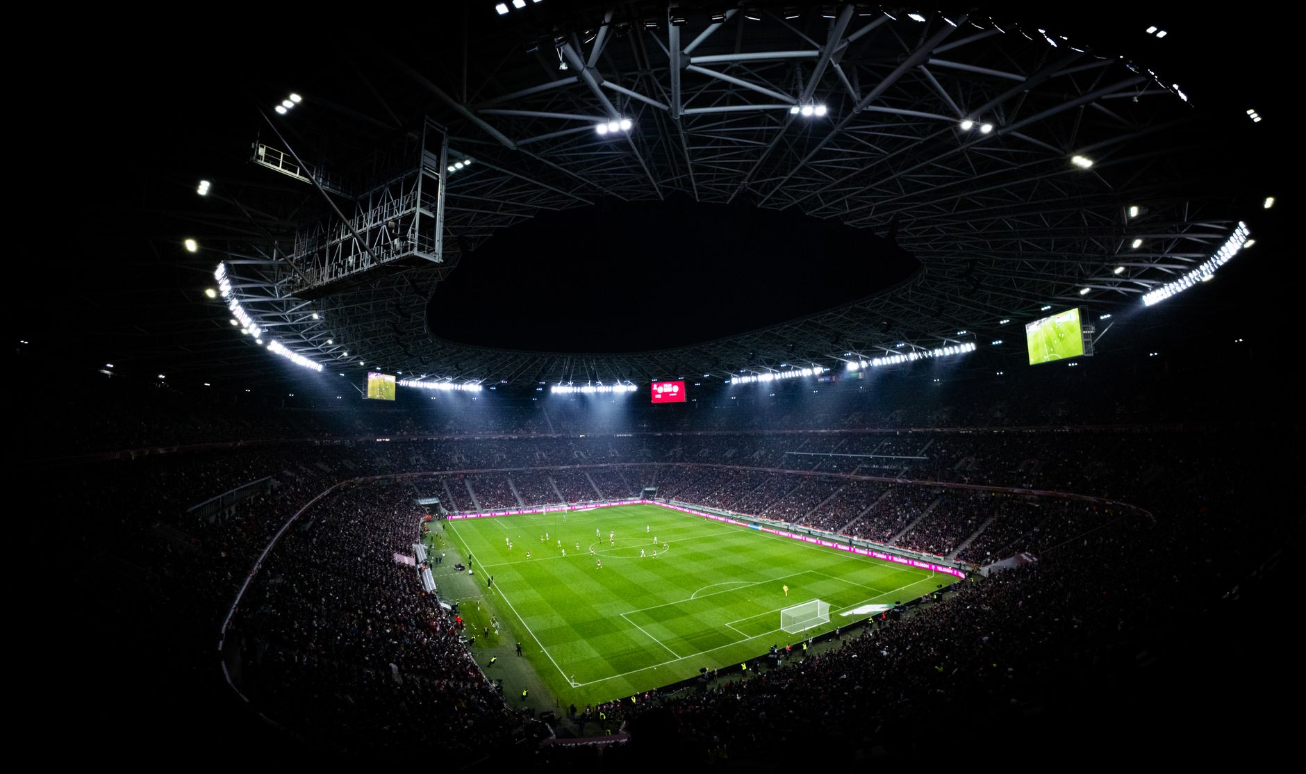 Nocny mecz piłkarski na oświetlonym stadionie z wypełnionymi trybunami